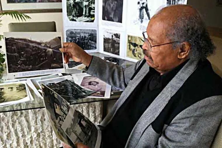 jRiordan17-a - Clarence H. Davis, 83, at his Cherry Hill home with a collection of photographs of his Korean War years. In the background are displays he made for presentations at local schools. Photo by Kevin Riordan