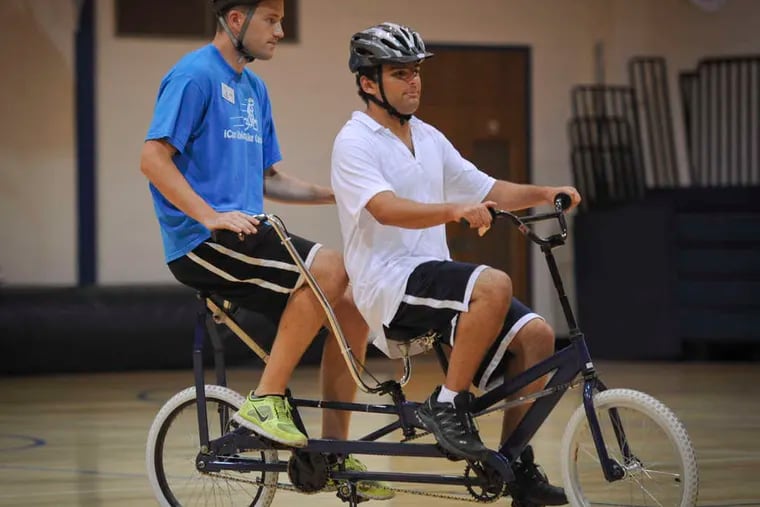 Camper Alex Newman (right) learns on a special tandem bike with iCan Ride's Kevin Crenshaw.