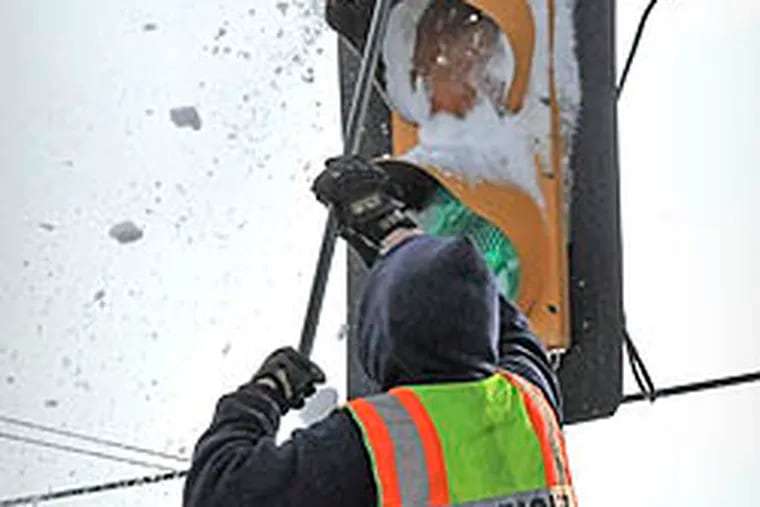 A firefighter stands on top of a fire truck to clear snow that was blocking the lenses of the traffic light in Willow Street Pa. Thursday, Jan.27, 2011. Wind-driven snow from Wednesday's storm covered all but a small part of the red lens on the traffic light. (AP Photo/Lancaster New Era, Blaine Shahan)