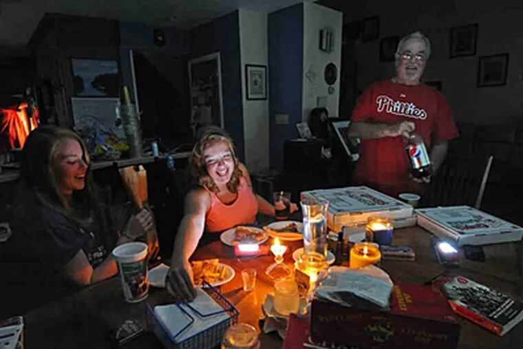 Laura (left), Emily, and Jim Cahill eat pizza by candlelight. Their Havertown home has not had power since Saturday. (April Saul/Staff)
