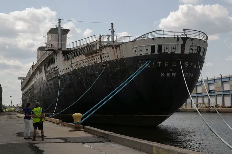 Susan Gibbs and Jorge Gonzalez look up at the SS United States ocean liner at Pier 82 in Philadelphia in July 2021.