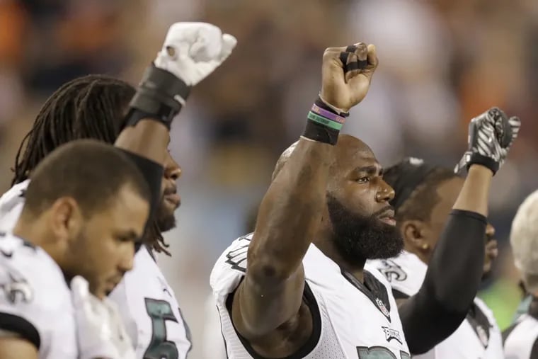 Eagles\' strong safety Malcolm Jenkins (center), defensive back Ron Brooks (right) and defensive end Steven Means stand with their first in the air during the national anthem.