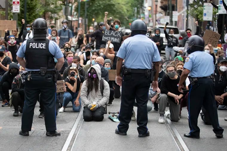Protesters take a knee on Walnut Street in front of a  row of police officers during Justice For George Floyd Philadelphia Protest on June 2.