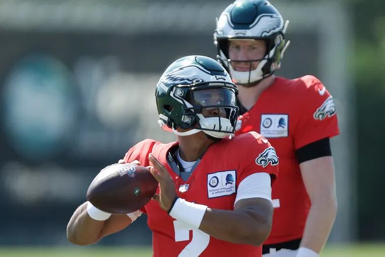 Carson Wentz watches rookie Jalen Hurts throw a pass during a recent Eagles practice session.