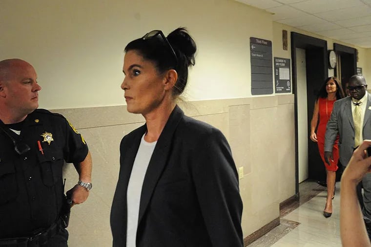Kathleen Kane's twin sister, Ellen Granahan, leads the way into Courtroom B at the Montgomery County Courthouse in Norristown. Attorney General Kathleen Kane (far right in red) follows on her way to her preliminary hearing.