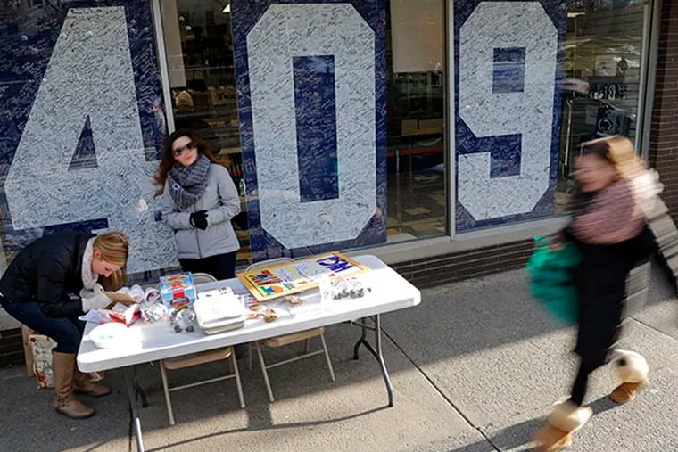 Penn State students Jackie Jones, left, of Pittsburgh, and Jacqueline Browne, center, from South River, N.J., man a bake-sale table in front of the Penn State Student Bookstore in State College, Pa., Friday, Jan. 16, 2015. (AP Photo/Gene J. Puskar)