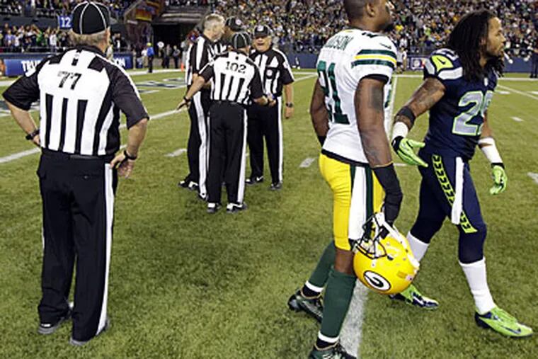 Replacement refs struggle to sort things out at the end of the Packers-Seahawks game Monday. (Ted S. Warren/AP)