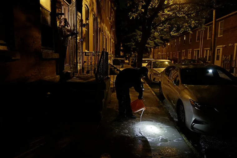 A man cleans blood off of the sidewalk in front of his Aunt’s home on the 1500 block of Bouvier St. in Phila., Pa. on May 18, 2022. Five people were shot on the block earlier in the evening.