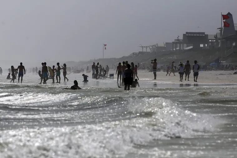 Beachgoers enter the water even though double-red flags are flying, warning of dangerous conditions and extremely rough surf in the remnants of Tropical Storm Cindy, in Seaside, Fla. (AP Photo/Kiichiro Sato)