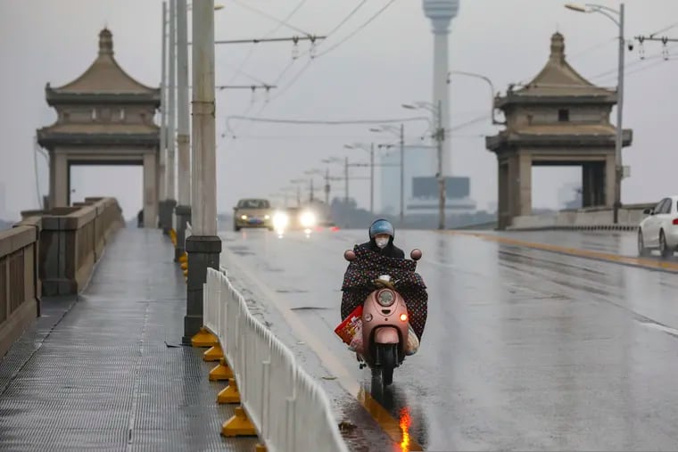 A motorcyclist rides across a bridge in Wuhan in central China's Hubei province last month. The virus-hit Chinese city of Wuhan, already on lockdown, banned most vehicle use downtown.