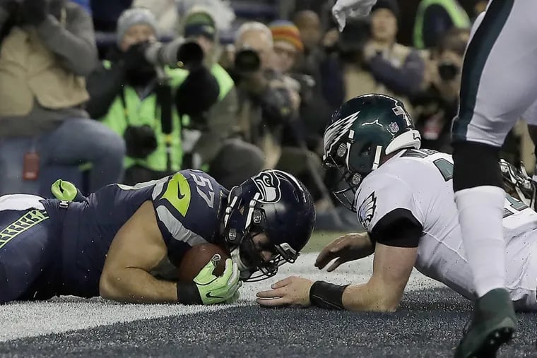The Seahawks’ Michael Wilhoite (left) falls on a fumble by the Eagles’ Carson Wentz.
