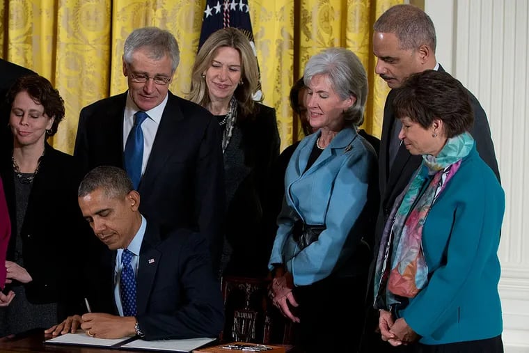 President Barack Obama signs a memorandum creating a task force to respond to campus rapes during an event for the Council on Women and Girls, Wednesday, Jan. 22, 2014, in the East Room of the White House in Washington. Standing behind him, from left are, Vice President Joe Biden, Sarah Rosenthal, White House Adviser on Violence Against Women, Education Secretary Arne Duncan, Director of the Domestic Policy Council Cecilia Muñoz, Defense Secretary Chuck Hagel, Elizabeth Sherwood-Randal, Health and Human Services Secretary Kathleen Sebelius, Attorney General Eric Holder, and White House Senior Adviser Valerie Jarrett. (AP Photo/Carolyn Kaster)