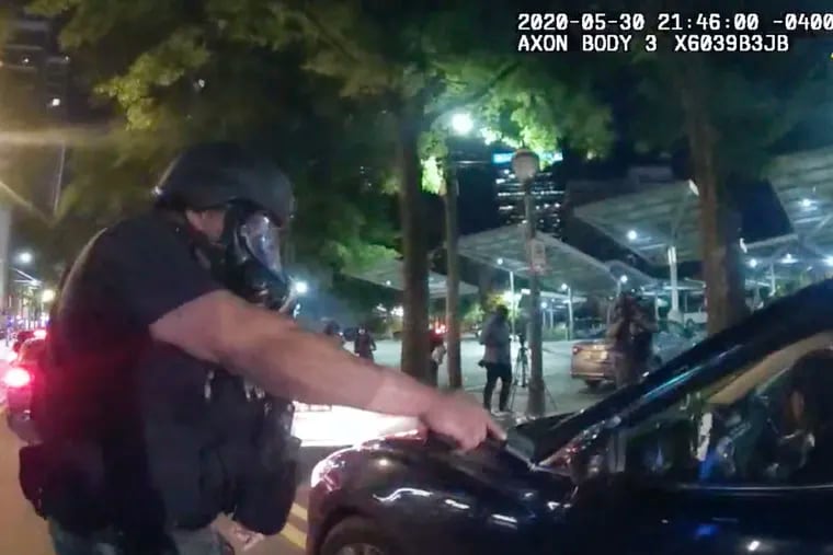 In this Saturday photo taken from police body camera video released by the Atlanta Police Department, an officer points his handgun at Messiah Young while the college student is seated in his vehicle, in Atlanta. The following day, Atlanta's mayor said two police officers were fired and three others placed on desk duty over excessive use of force during the arrest of Young and fellow college student Taniyah Pilgrim, seated in the passenger side of the car.