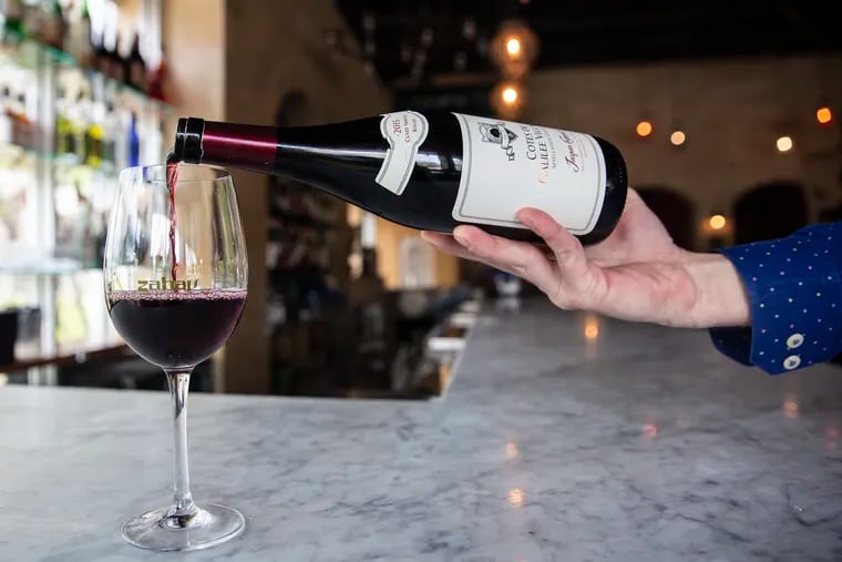 Jeff Bartash, beverage manager at Zahav, pours a bottle of kosher wine at the restaurant on Thursday, April 11, 2019.