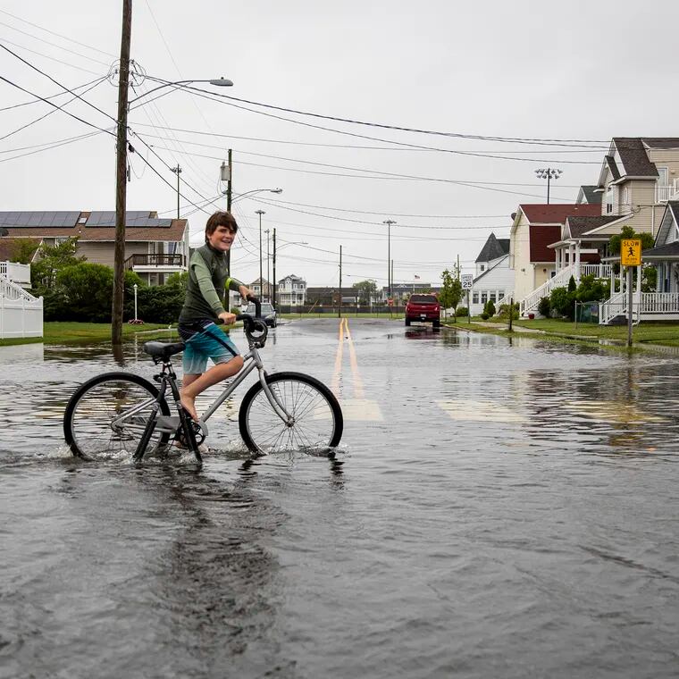 A teenager bikes through the flood waters at Fourth Street and Simpson Avenue in Ocean City three summers ago. It was possible flooding might close some streets Saturday night.