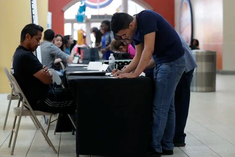 In this Oct. 1, 2019, file photo Billy Ramos, right, fills out a job application with Adidas during a job fair at Dolphin Mall in Miami. On Friday, Nov. 1, the U.S. government issues the October jobs report.