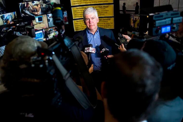 FILE - In this Monday, June 6, 2016 file photo, journalists surround around Gov. Rick Snyder to ask him questions about the Flint water crisis. Authorities investigating the crisis have used search warrants to seize from storage the state-owned mobile devices of Snyder and 65 other current or former officials, The Associated Press has learned.(Jake May/The Flint Journal - MLive.com via AP)