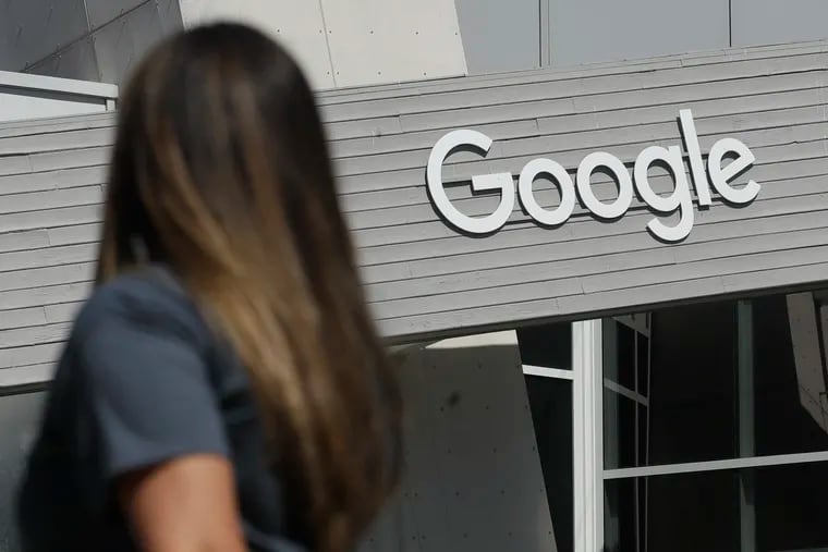 A woman walks below a Google sign on the campus in Mountain View, Calif.