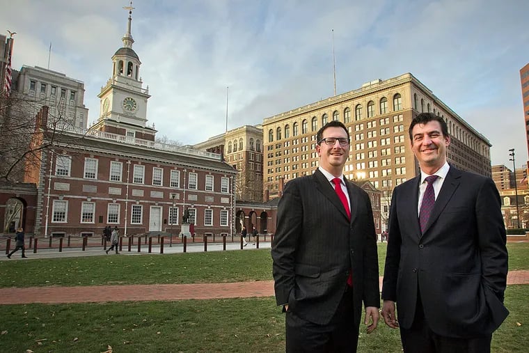 Andrew Hohns, USA250's board chairman (right), and Jon Grabelle Herrmann, the nonprofit organization's only employee, stand in front of Independence Hall, near the organization's offices.