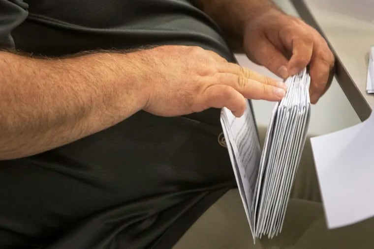 Kevin Richardson, administrator with Philadelphia City Commissioner,  looks through a stack of mail ballots in 2022.