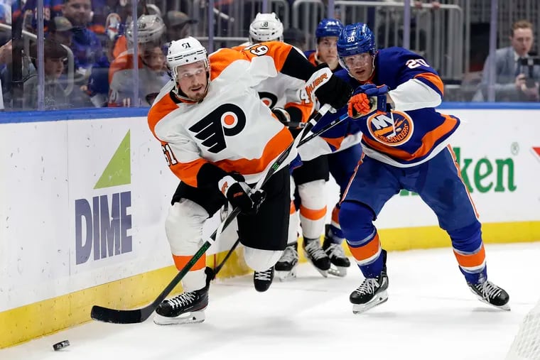 Philadelphia Flyers defenseman Justin Braun (61) skates with the puck past New York Islanders right wing Hudson Fasching in the second period of an NHL hockey game Saturday, April 8, 2023, in Elmont, N.Y. (AP Photo/Adam Hunger)