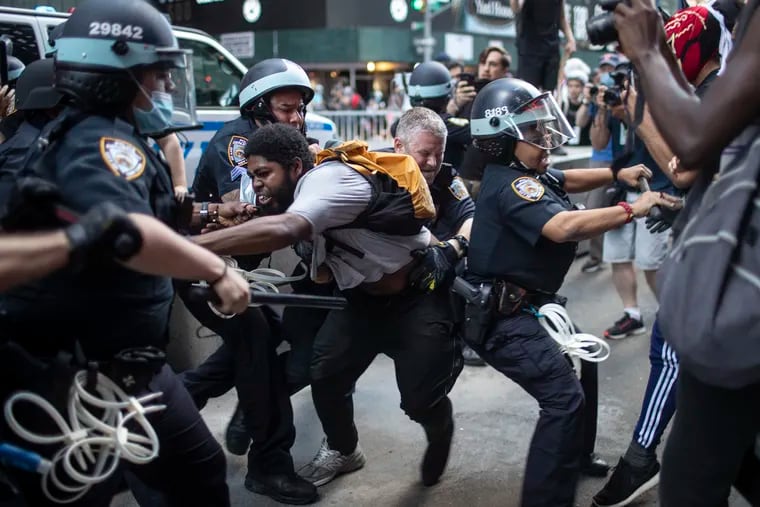 Police detain protesters as they march down the street during a solidarity rally for George Floyd, Saturday in New York.