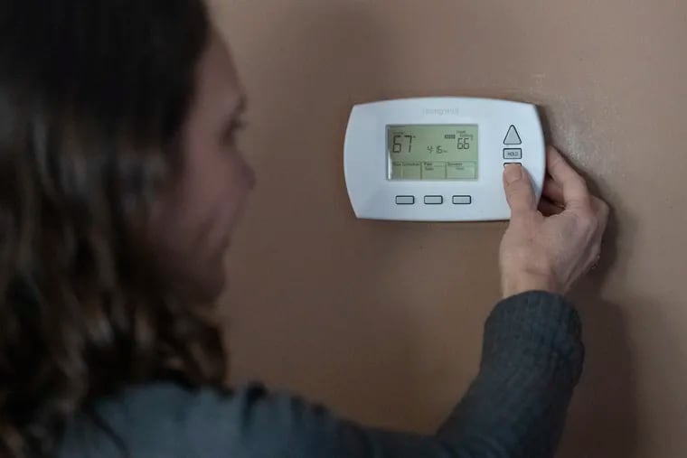 Sophie Alfonsi-Connaire turns down the thermostat at her home in Havertown, Pa., on Monday, Jan. 30, 2023, as many faced high heating bills.