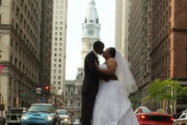 The couple kiss in Center City as William Penn watches from atop City Hall.