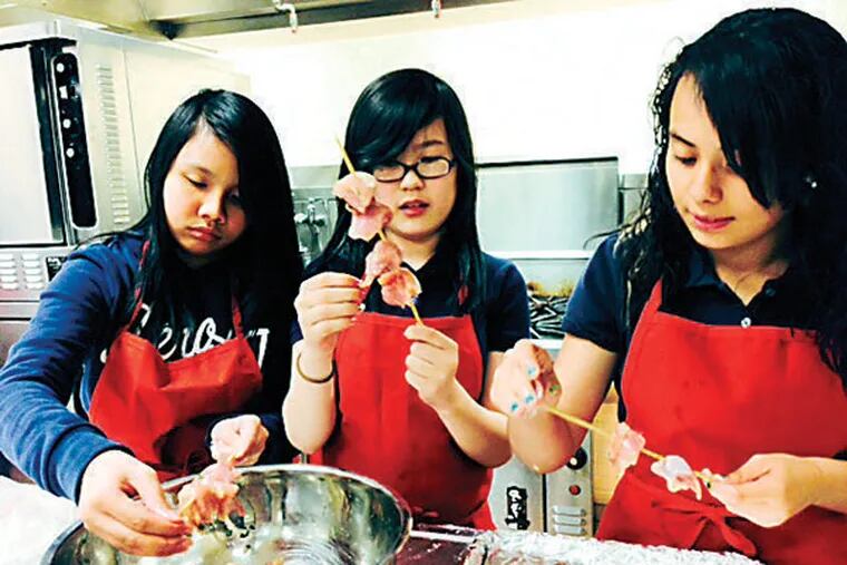 Jenny Bui, Sandy Phuong, and Jasmine Sotelo thread chicken onto skewers. Juniata Park Academy week 6. (Photo by Cindy Rappoport)