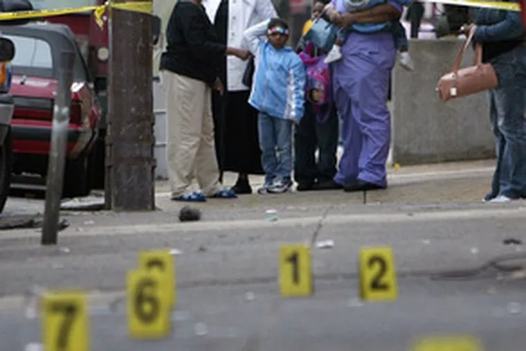 Neighbors look down a sidewalk covered with evidence markers Saturday as police investigate a homicide at 19th Street and Girard Avenue.